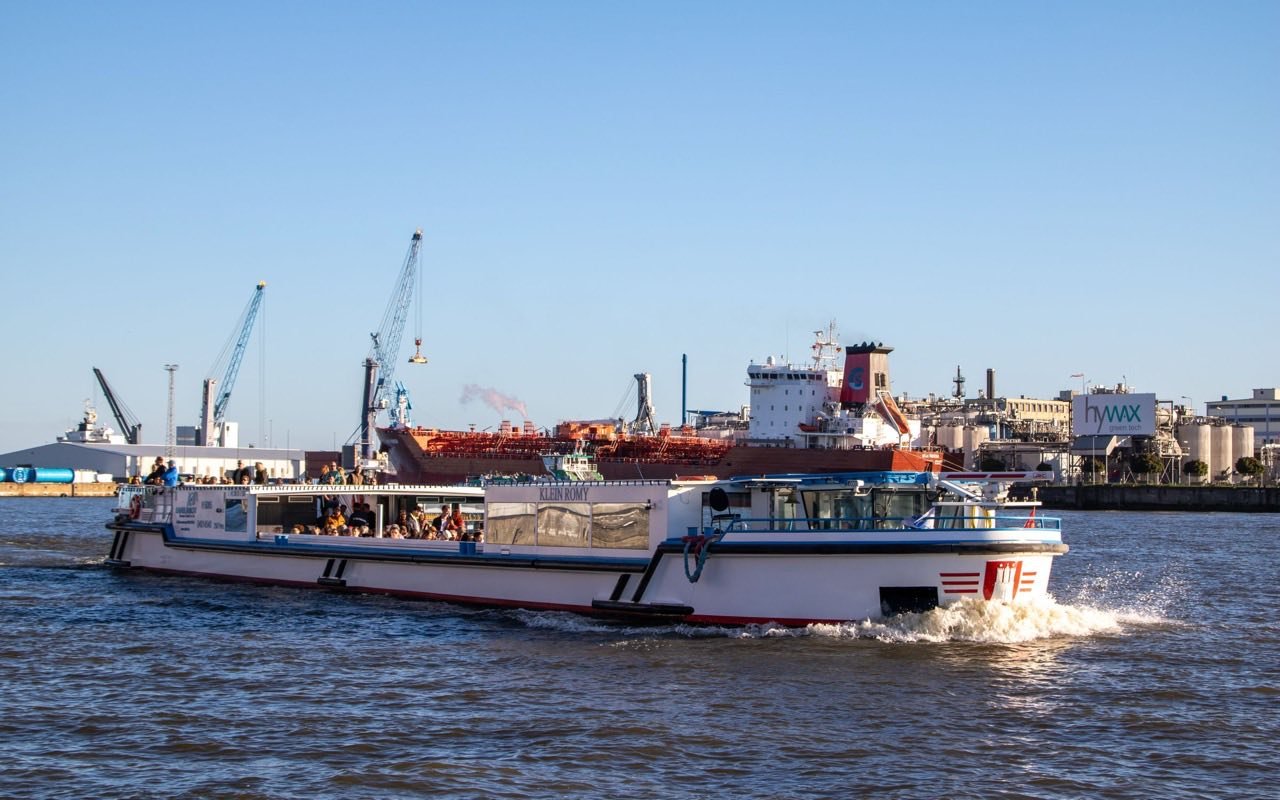 Symbolbild Eventlocation: Ausflugsboot fährt bei Sonne durch den Hamburger Hafen