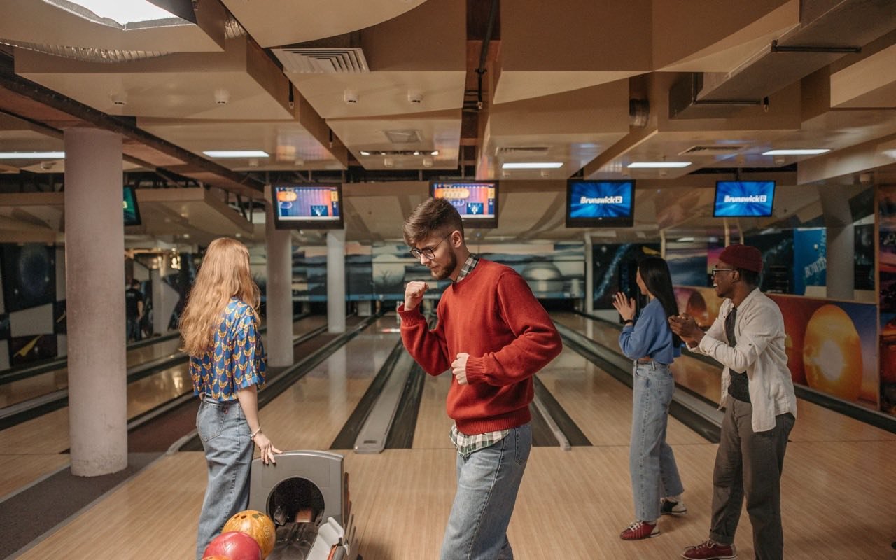 Symbolbild Bowling: Gruppe Erwachsener jubelt gemeinsam beim Bowling in der Halle