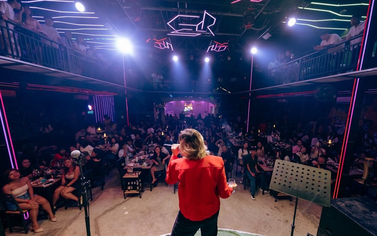 Symbolbild Varieté/Show: Künstlerin auf Bühne vor vollem Saal mit Publikum an Tischen