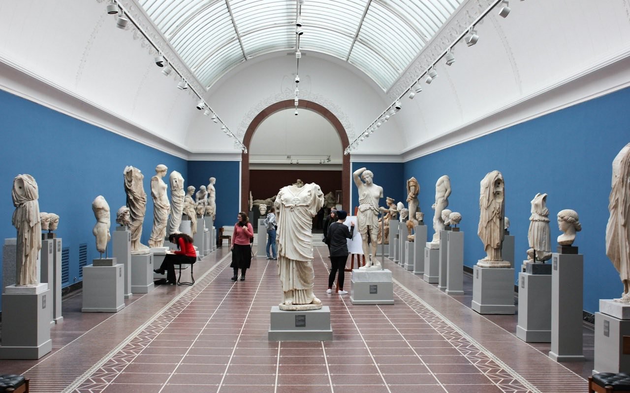 Symbolbild Immersive Ausstellung: Besucher in heller Skulpturenhalle mit antiken Statuen