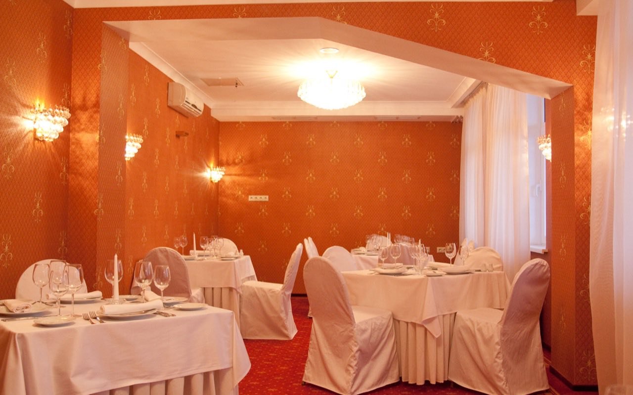 Symbolbild Partyraum: Kleiner Festsaal mit gedeckten Tischen in warmem Licht