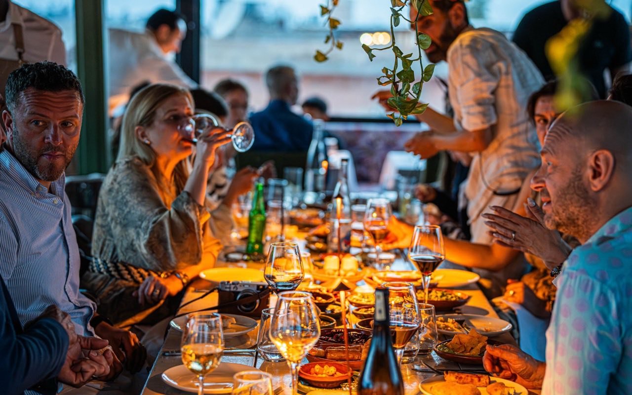 Symbolbild Restaurant mit Nebenräumen: Freunde feiern an langer Tafel bei Kerzenlicht mit Wein