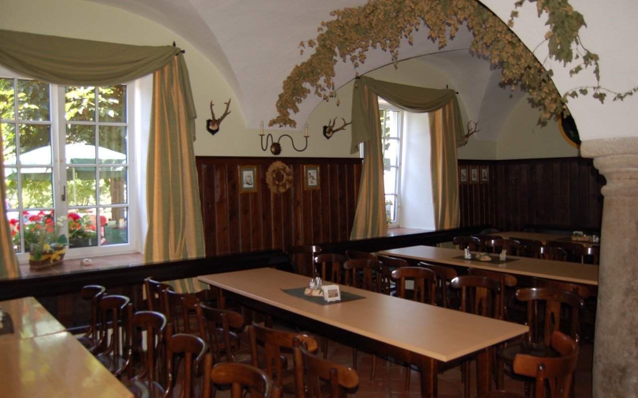 Symbolbild Restaurant mit Gruppenraum: Gaststube mit Holztischen und hellen Fenstern